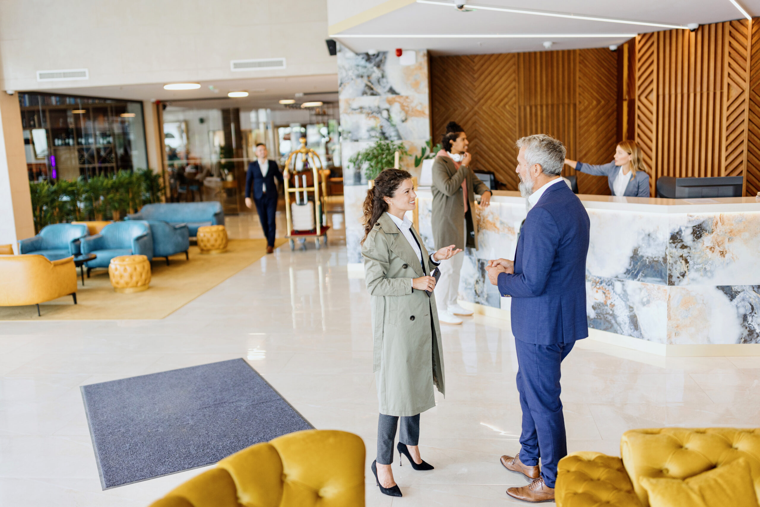 Modern man and woman talking in front of the reception of a luxury hotel